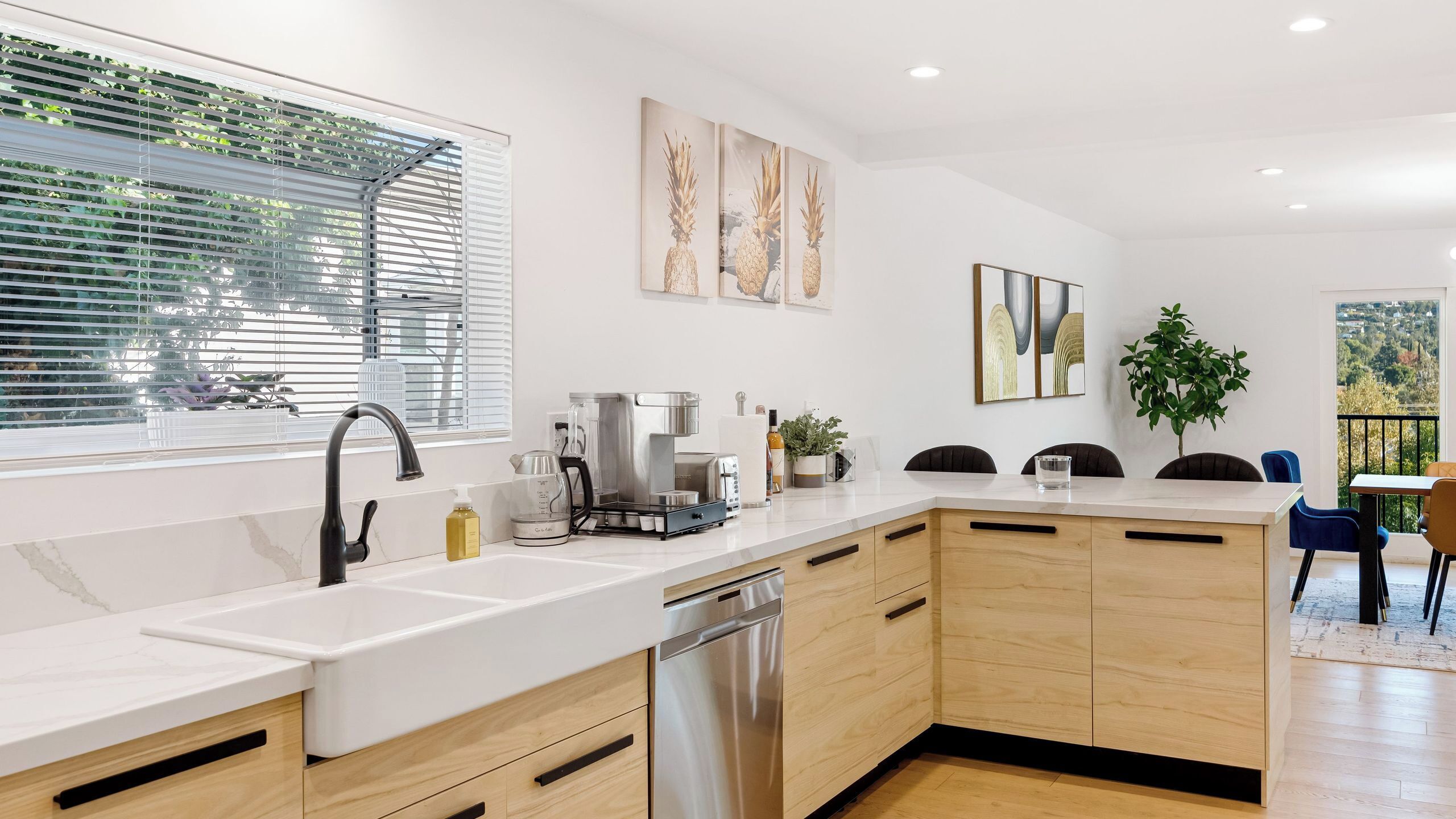 A modern kitchen with a dishwasher, coffee maker, and a view of the outdoors.