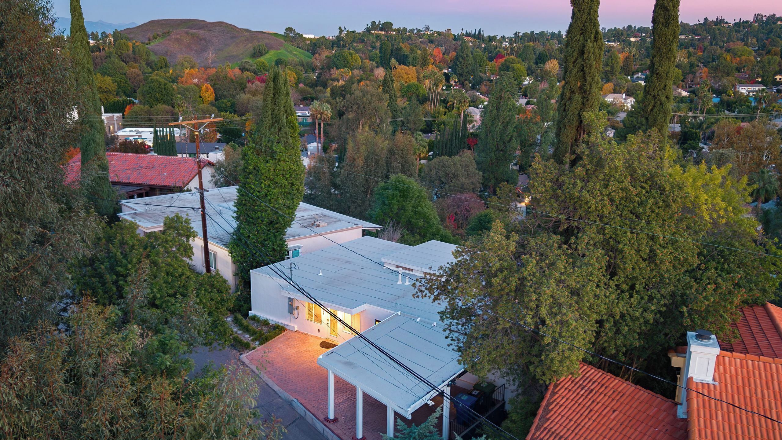 Uma área residencial com casas, árvores e uma colina ao fundo.