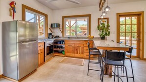 A kitchen with a refrigerator, stove, wooden cabinets, a sink, and a window.