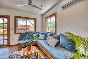 A modern living room with a blue sofa, a wooden coffee table, and a potted plant. - Papaya, 2 bed, 2 bath, poolside, 5 min walk to surf at TropicalArts Bocas (Bocas del Toro)