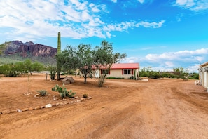 Paisaje desértico con un edificio de techo rojo y un camino de tierra.