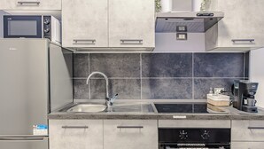Eine moderne Küche mit integriertem Mikrowellenherd, einer Kaffeemaschine und einer Spüle aus Edelstahl.