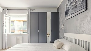 Ein Schlafzimmer mit einem Bett, einem Heizkörper, einem Fenster und einem grauen Kleiderschrank.