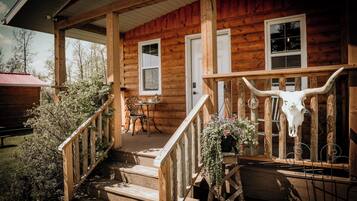 A wooden cabin with a porch, steps, and a large bull skull decoration.