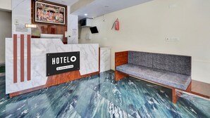 A hotel reception area with a marble reception desk, a sofa, a ceiling fan, and a fire extinguisher. - Deluxe With Twin Bed Lotus Park Hotel (Visakhapatnam)