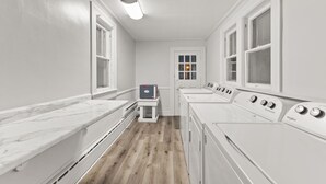 A laundry room with white appliances, a marble countertop, and a wooden floor.