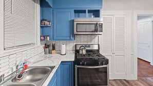 A kitchen with blue cabinets, a stainless steel microwave, a gas stove, and an oven.