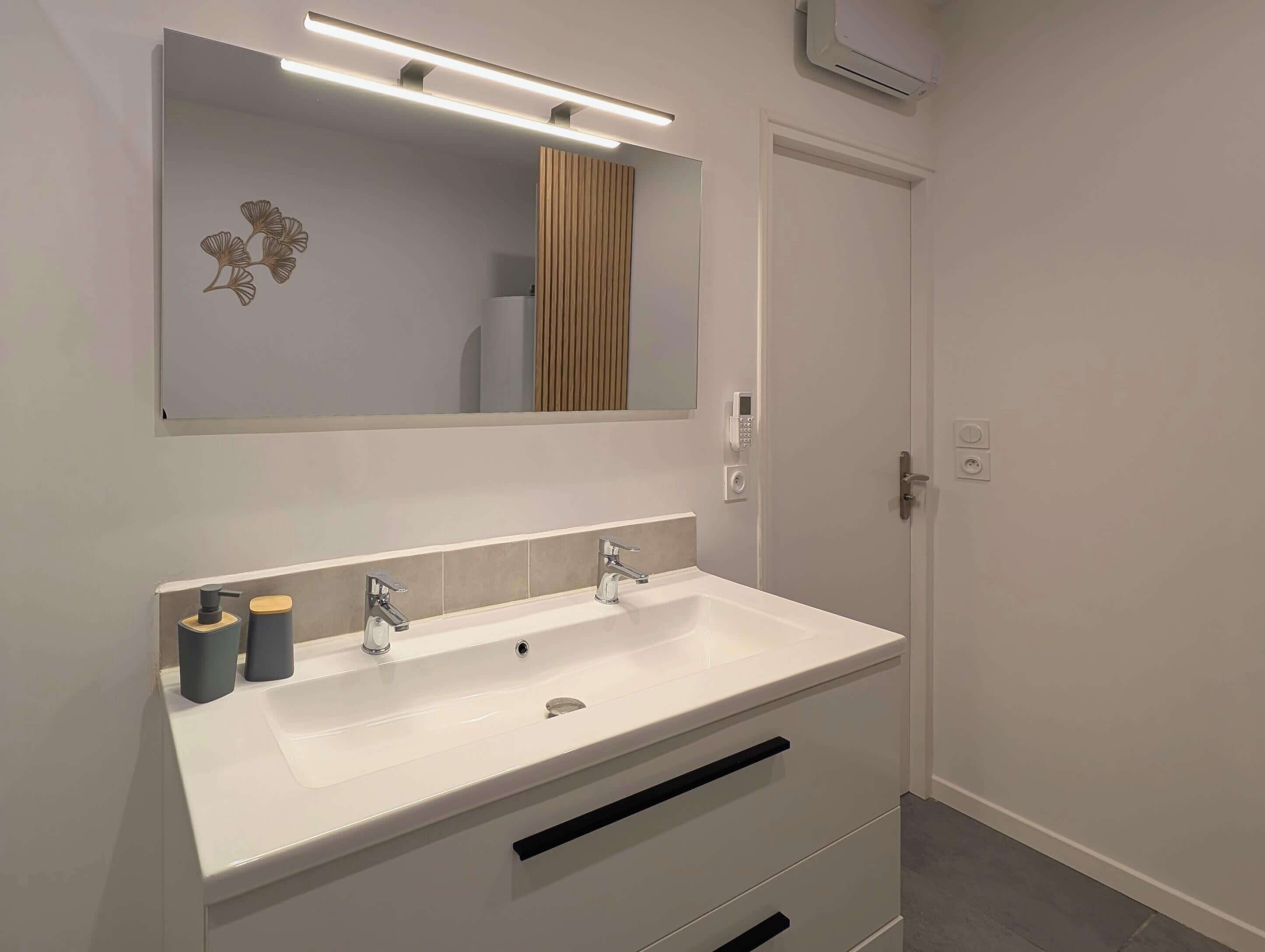 A bathroom with a white sink, two faucets, a mirror, and a towel rack.