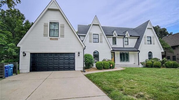 Une maison à deux étages avec un garage, une pelouse devant et une allée.
