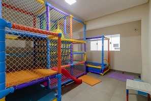 A play area with a netted structure, a slide, and a small table. - Apto p 6 Pessoas a 400m da Praia das Pitangueiras (Guarujá)