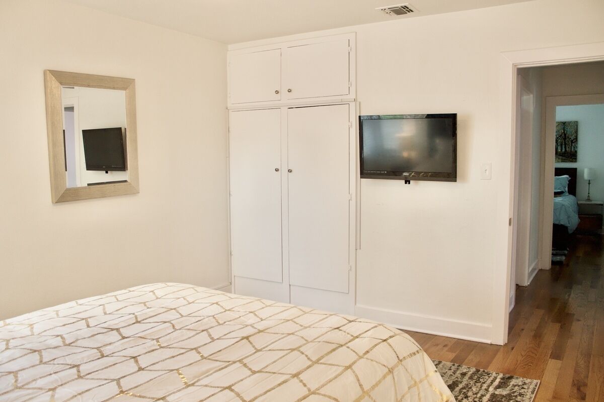 A bedroom with a bed, a wardrobe, a television, and a mirror.