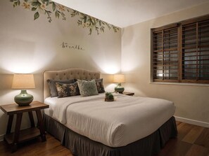 A bedroom with a tufted headboard, two bedside tables with lamps, a window with wooden shutters, and a floral wall decal. - Pool Table Fire Pit Spacious Disney Retreat (Placentia)