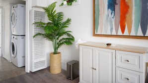 Een wasserette met gestapelde wasmachines en drogers, een potplant en een aan de muur hangend kunstwerk.