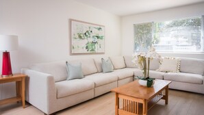 A living room with a beige sofa, a wooden coffee table, and a red lamp.
