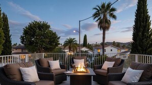 An outdoor seating area with wicker furniture and a central fire feature.