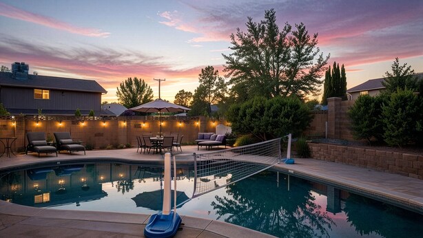 A swimming pool with a deck, lounge chairs, and a table with umbrellas.