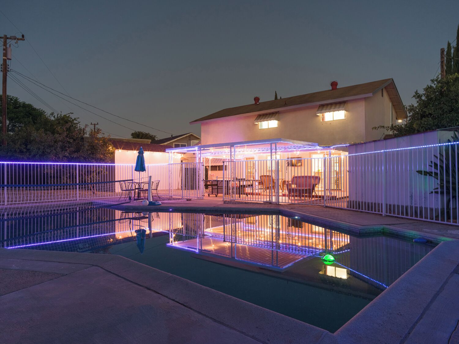 Un giardino privato con piscina, una veranda coperta e un recinto.