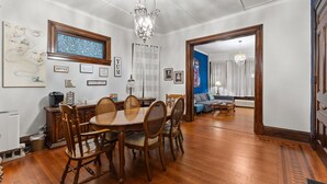 A dining area with a wooden table and chairs, a chandelier, and framed artwork on the walls. - The Duchess Guest House, Walk to Downtown Anderson, Historic! (Anderson)