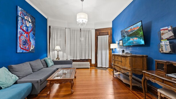 A living room with a blue wall, a sofa, a coffee table, a TV, and a wooden cabinet. - The Duchess Guest House, Walk to Downtown Anderson, Historic! (Anderson)
