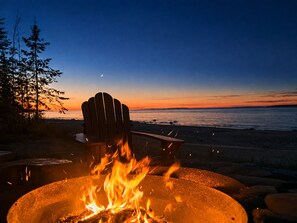 A fire pit with a chair and a view of the ocean at sunset. - Lake Huron Beach House 10 minutes from Mackinaw City, Kayaks, Gym, Amazing Views (Cheboygan)