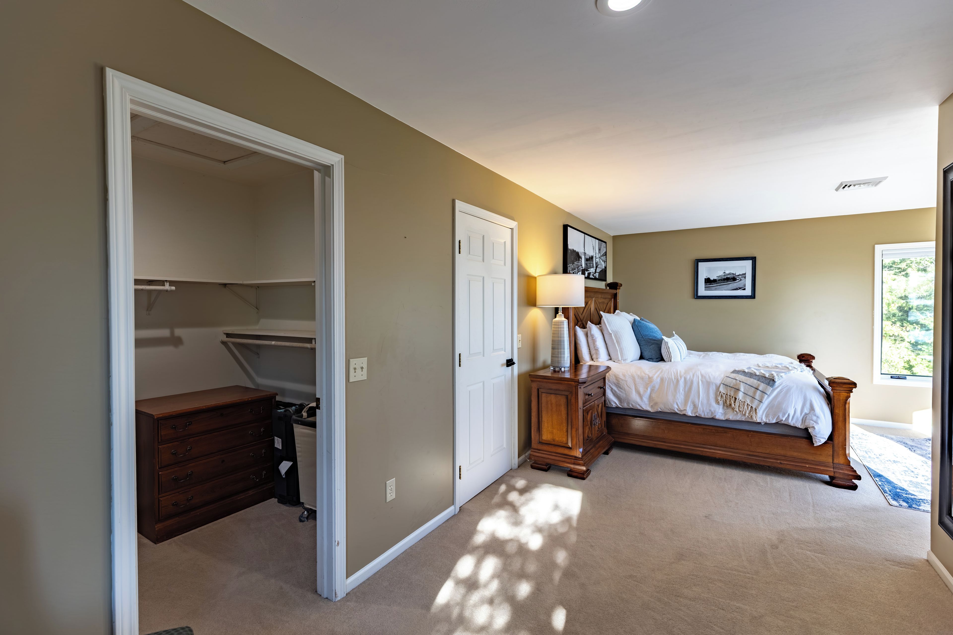 A bedroom with a bed, a nightstand, a dresser, and a closet.