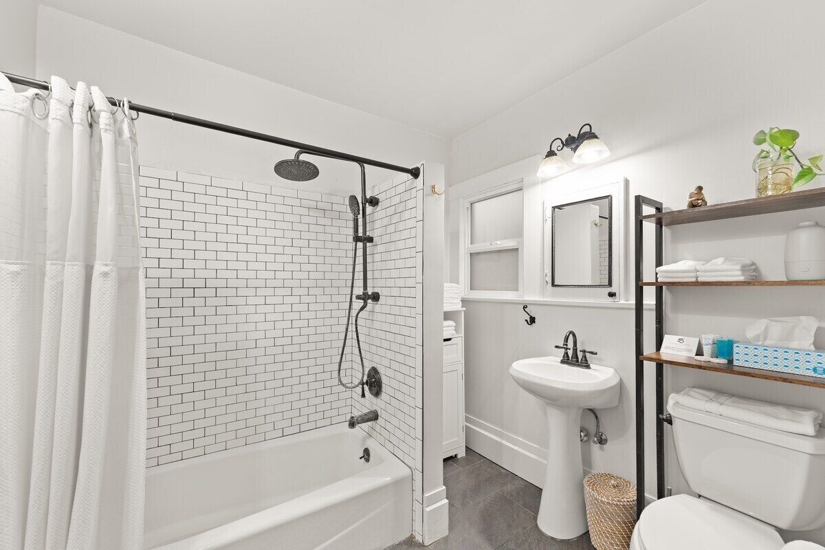 A modern bathroom with a white bathtub, a shower, a sink, and a toilet.