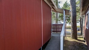 A covered wooden deck leading to a building with a red exterior. - Siljansbadets Camping (Rattvik)