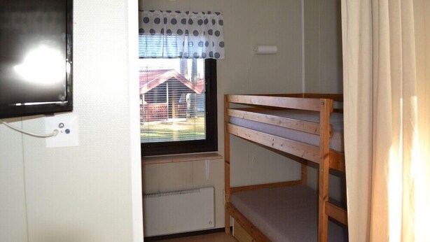 A bunk bed room with a window, a radiator, and a wall-mounted TV. - Siljansbadets Camping (Rattvik)