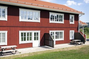 Un edificio rojo con detalles blancos, numerosas ventanas y una mesa de picnic en el exterior.