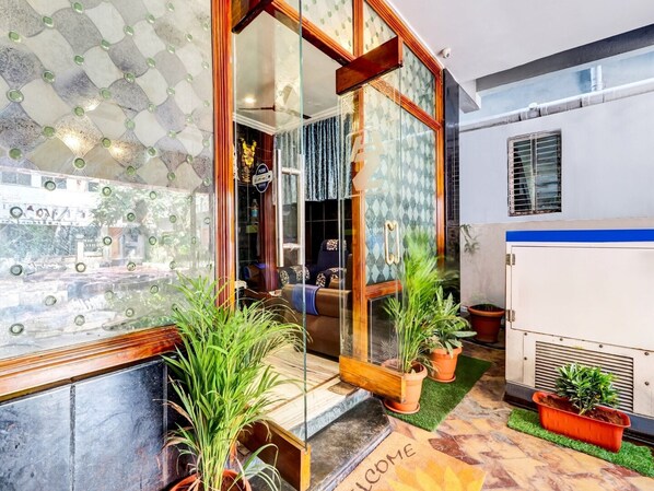 A modern interior with a glass door entrance, potted plants, and a welcome mat.