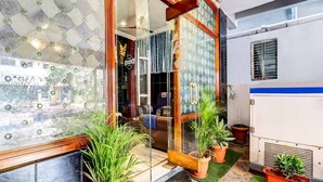 A modern interior with a glass door entrance, potted plants, and a welcome mat. - Hotel O Hanuman Pet Railway Station (Vijayawada)