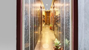 A corridor with marble walls, potted plants, and a staircase leading to an upper level. - Hotel O Hanuman Pet Railway Station (Vijayawada)