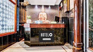 A reception desk with a Buddha statue, a sign reading 'HOTEL O,' and a company-serviced label. - Hotel O Hanuman Pet Railway Station (Vijayawada)