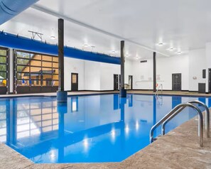 An indoor swimming pool with clear blue water, a tiled floor, and a metal ladder. - On the Rocks Lodge - Sleeps 18 (Branson)