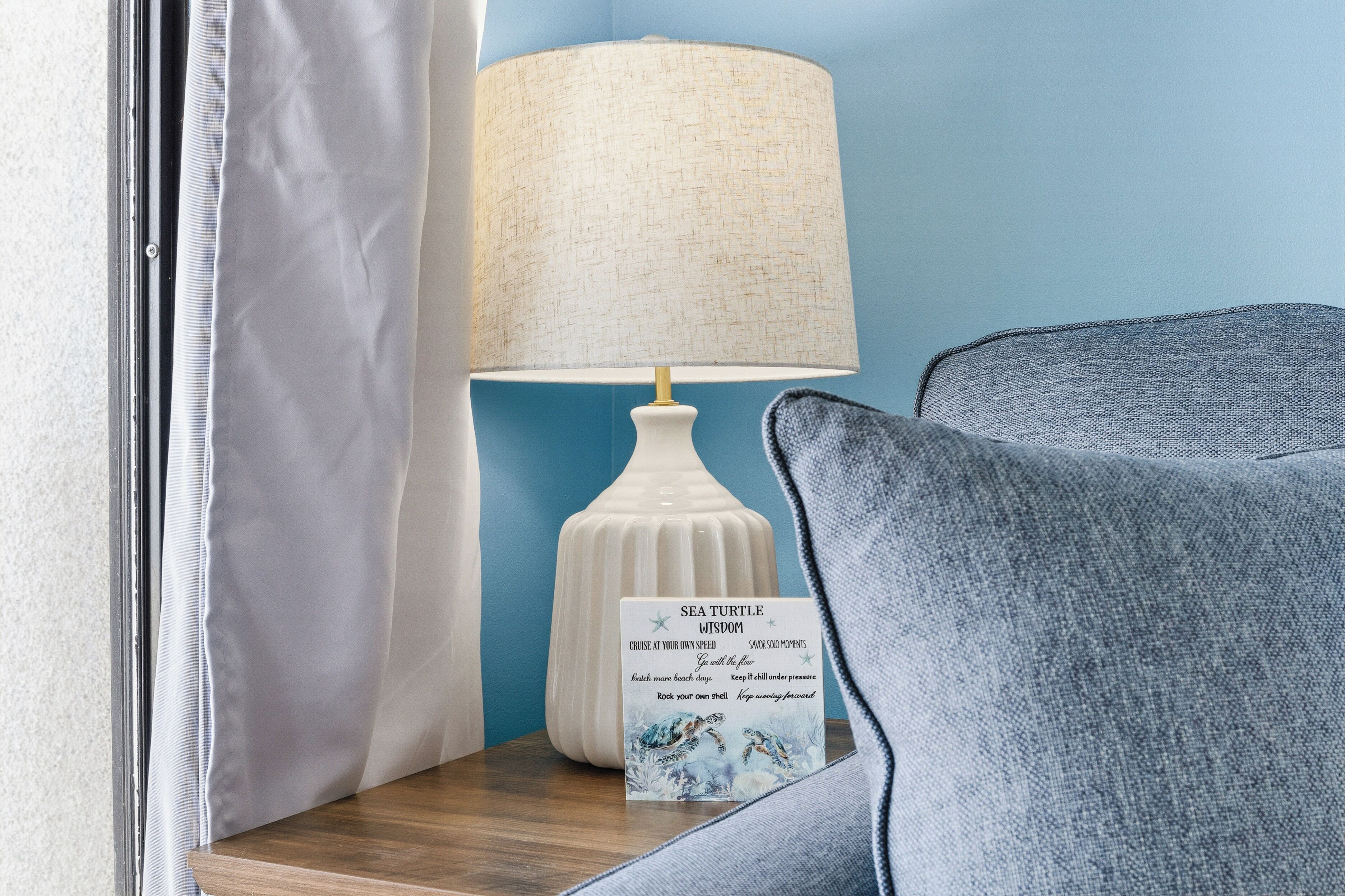 A room with a white lamp, a framed quote, and a blue wall.