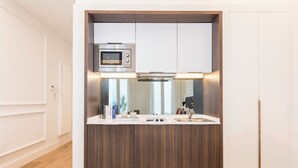 Una cocina compacta con microondas integrado, campana extractora de acero inoxidable y encimera blanca.