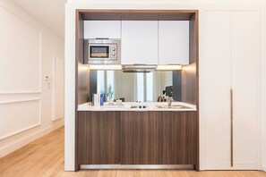 A compact kitchen with a built-in microwave, a stainless steel range hood, and a white countertop. - Victoria XVI - Studio Apartment, Sleeps 2 (Malaga)
