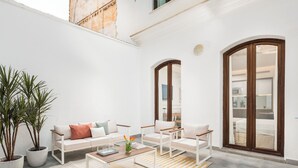 Una sala de estar moderna con un sofá, sillones, una mesa de centro y plantas en macetas.