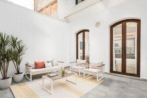 A modern living room with a sofa, chairs, a coffee table, and potted plants. - Victoria XVI - Studio Apartment, Sleeps 2 (Malaga)
