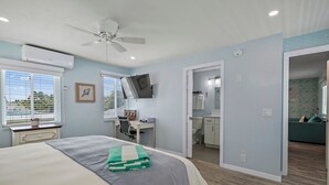 Een slaapkamer met een bed, bureau, televisie en airconditioning.