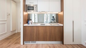 A compact kitchen with a microwave, sink, and wooden cabinets. - Victoria XIX - Studio Apartment, Sleeps 2 (Malaga)
