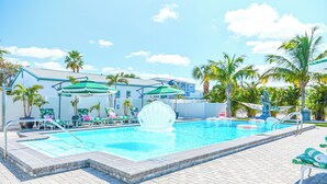 A swimming pool with a shell-shaped fountain, lounge chairs, and umbrellas. - Unit 104 King Suite 1 Bed/1Bath - Partial view - The Pearl Cabana Club (St Pete Beach)