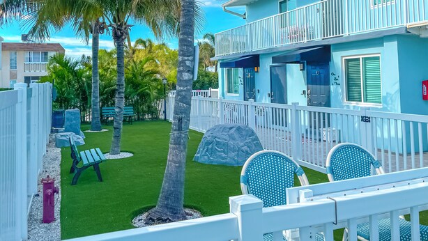 A resort with a pool, lounge chairs, and a building with a balcony. - Unit 105 King Suite 1 Bed/1 Bath - The Pearl Cabana Club (St Pete Beach)