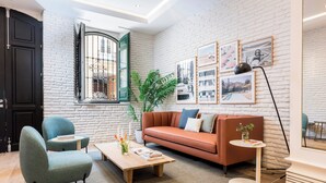 Una sala de estar moderna con un sofá, sillas, una mesa de centro y obras de arte en las paredes.