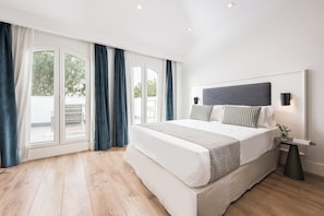 Een moderne slaapkamer met een groot bed, een hoofdeinde, een nachtkastje met een lamp en uitzicht door een glazen deur.