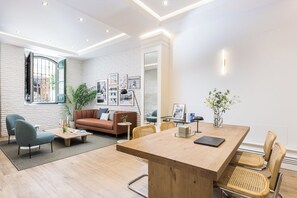 Een moderne woonkamer met een houten eettafel, comfortabele zitplaatsen, een bank en een groot raam.