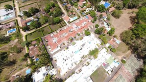 An aerial view of a residential area with multiple houses, a swimming pool, and a tennis court.
