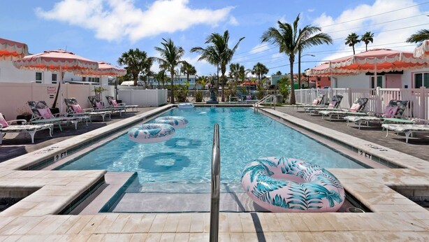 A swimming pool with lounge chairs and palm trees. - Unit 112 Studio King Suite - The Pearl Cabana Club (St Pete Beach)