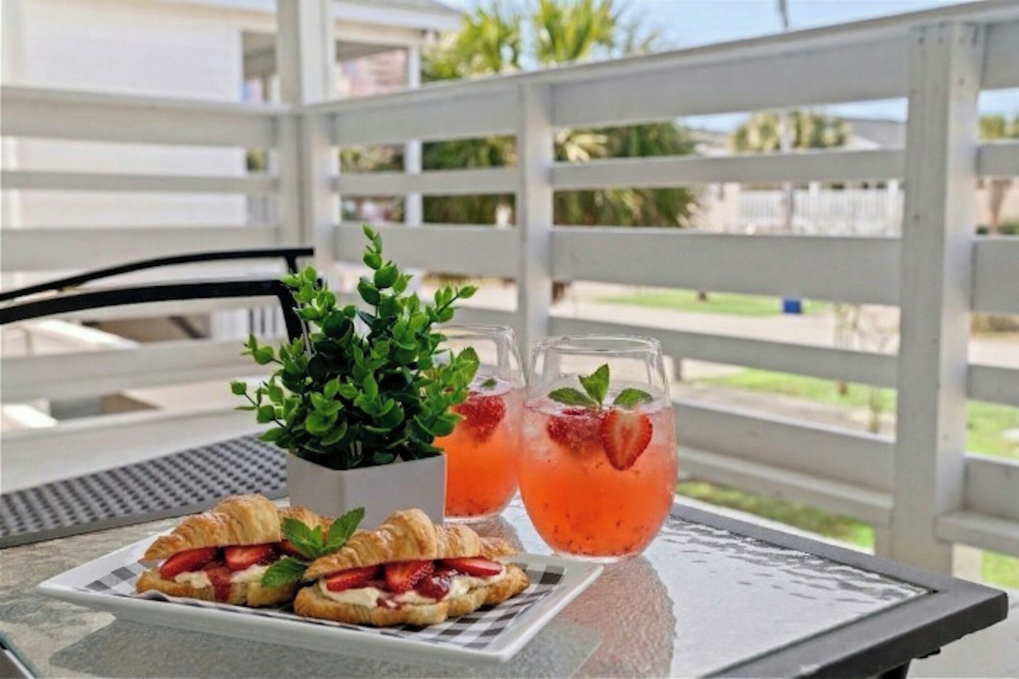 A table with two drinks, a plant, and two pastries.