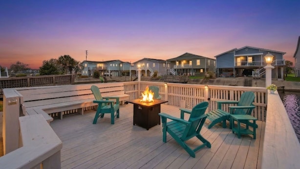 A deck with chairs, a fire pit, and a view of houses.